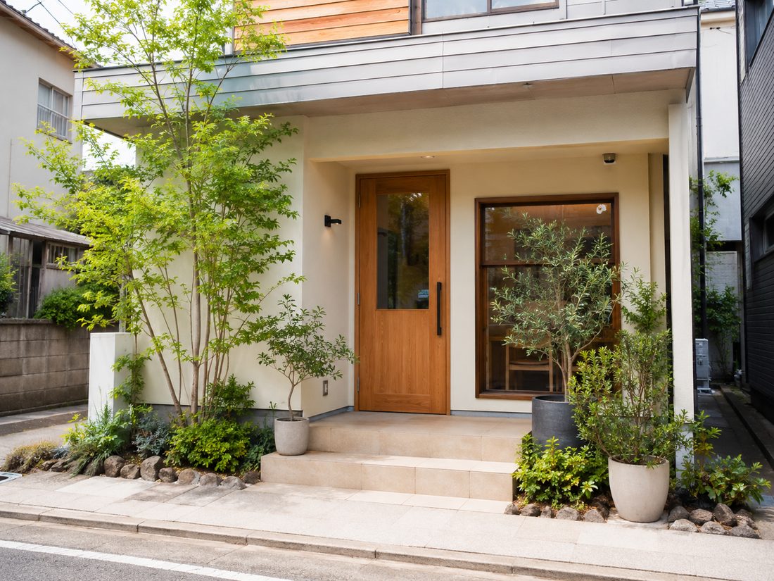 木製のドアと植栽が目印の、めぐる整体院の外観