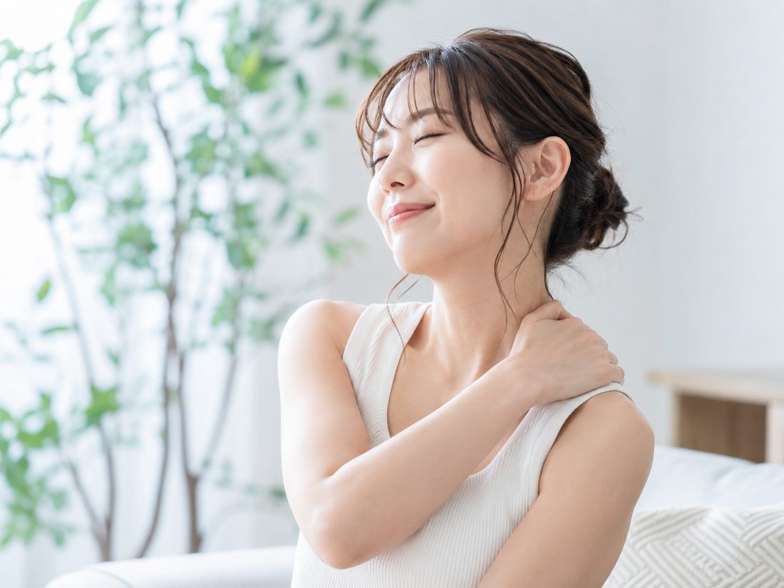 肩に手を当てて首・肩の調子を確かめる女性